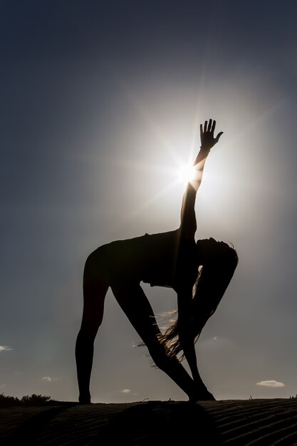 Ritratto di una donna che fa yoga sulla spiaggia