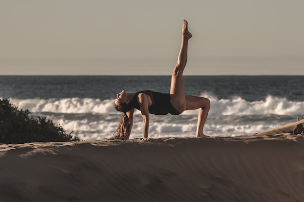 Ritratto di una donna che fa yoga sulla spiaggia