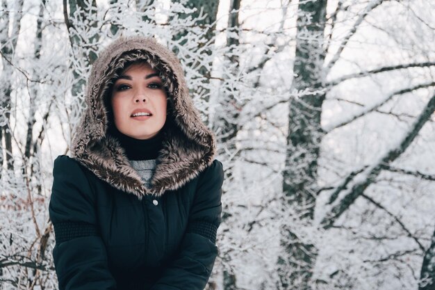 Ritratto di una donna che indossa un cappotto di pelliccia in piedi contro gli alberi durante l'inverno