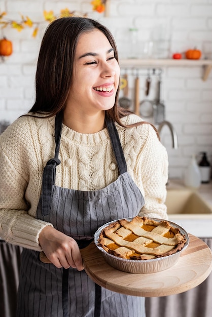Ritratto di una donna che prepara la torta di zucca per la cena di ringraziamento nella cucina di casa