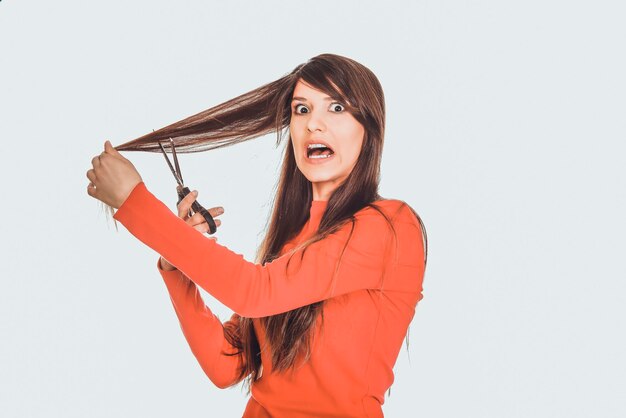 Ritratto di una donna che taglia i capelli su uno sfondo bianco