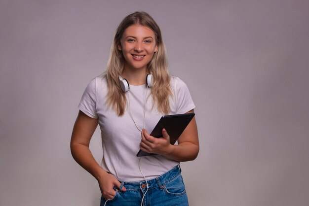 Ritratto di una donna che tiene in mano un tablet isolato su uno sfondo grigio e che guarda la telecamera