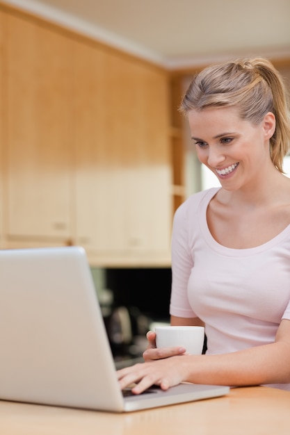 Ritratto di una donna che utilizza un computer portatile mentre bevendo tè