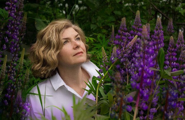 Ritratto di una donna con fiori viola contro le piante