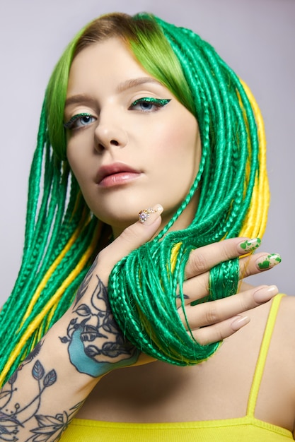 Ritratto di una donna con i capelli creativamente colorati in colore verde e giallo.