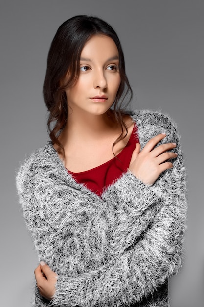 Ritratto di una donna con i capelli lisci che si avvolge in un maglione soffice