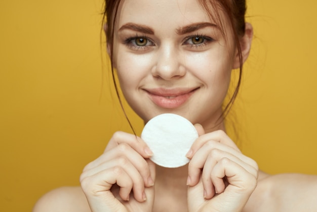 Ritratto di una donna con tamponi di cotone in mano su uno sfondo giallo beauty studio