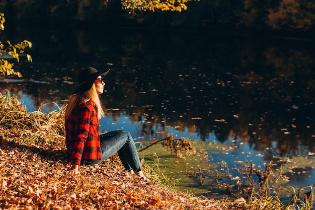 Ritratto di una donna con un cappello nero al lago