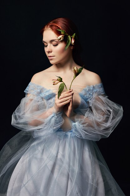 Ritratto di una donna con un fiore medievale tra le mani sulla copertina del libro. Perfetta bellezza naturale di una ragazza con i capelli lunghi