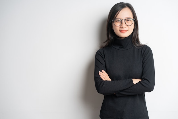 Ritratto di una donna d'affari asiatica sorridente in piedi con le braccia incrociate e con gli occhiali