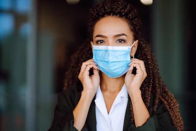 Ritratto di una donna d'affari che indossa una maschera protettiva e guarda a porte chiuse.