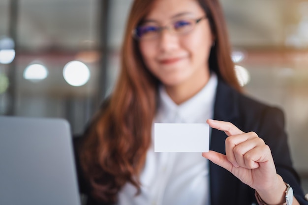 Ritratto di una donna d'affari con una carta vuota mentre usa un portatile alla scrivania in ufficio