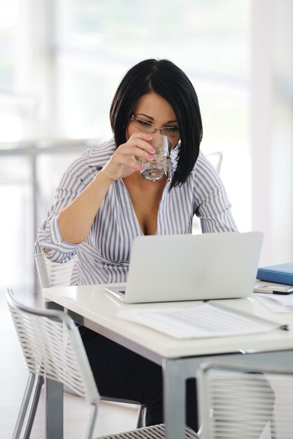 Ritratto di una donna d&#39;affari di lavoro seduto alla sua scrivania con un computer portatile che sembra felice