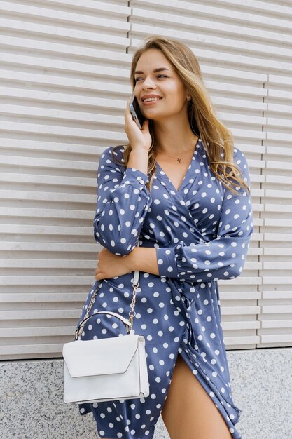 Ritratto di una donna d'affari di successo in un vestito blu che sta parlando al telefono fuori