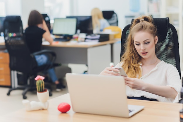 Ritratto di una donna d'affari seria utilizzando il computer portatile in ufficio Bella donna hipster prendendo appunti in ufficio moderno