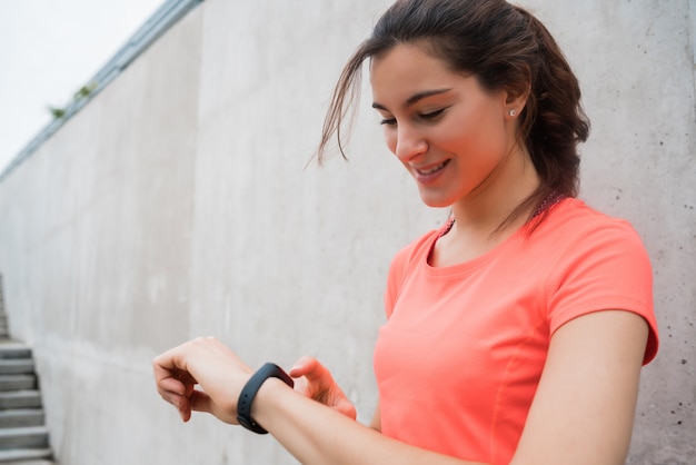 Ritratto di una donna di forma fisica che controlla il tempo sul suo orologio intelligente. Sport e concetto di stile di vita sano.