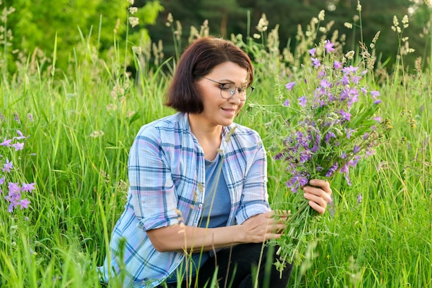 Ritratto di una donna di mezza età con un bouquet di fiori di campo in natura