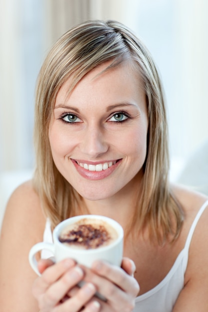 Ritratto di una donna felice che beve un caffè seduto su un divano