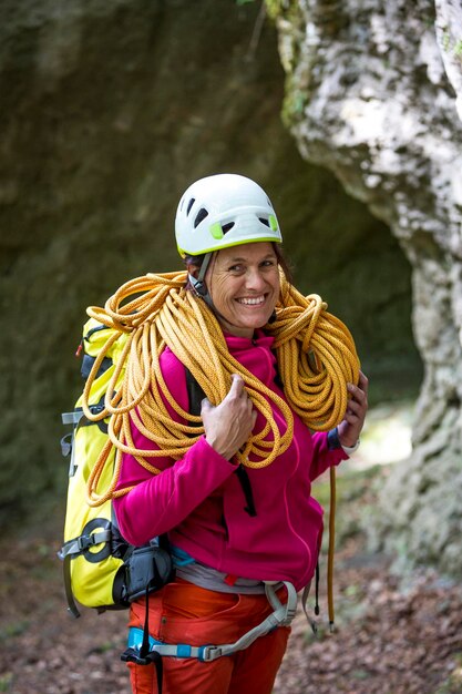 Ritratto di una donna felice che porta una corda mentre si trova contro le rocce