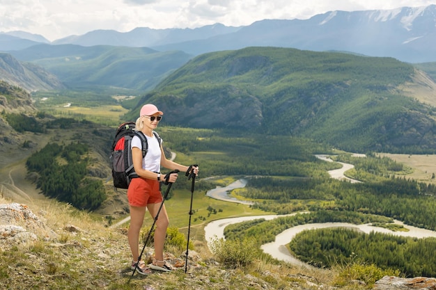 Ritratto di una donna felice escursionista in piedi sulla cima della montagna e godendo della libertà e della giornata di sole Escursionismo di viaggio e concetto di stile di vita attivo