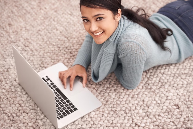 Ritratto di una donna felice sul tappeto con un portatile rilassarsi e navigare con lo studio di ricerca e web nel soggiorno Studente universitaria sul pavimento con computer e lezioni online a casa