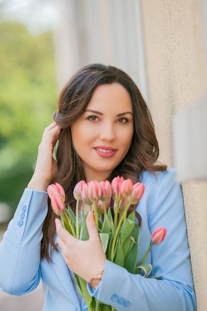 Ritratto di una donna in abito blu con un mazzo di tulipani