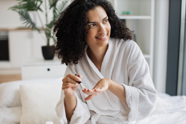 Ritratto di una donna in accappatoio bianco che fa la manicure