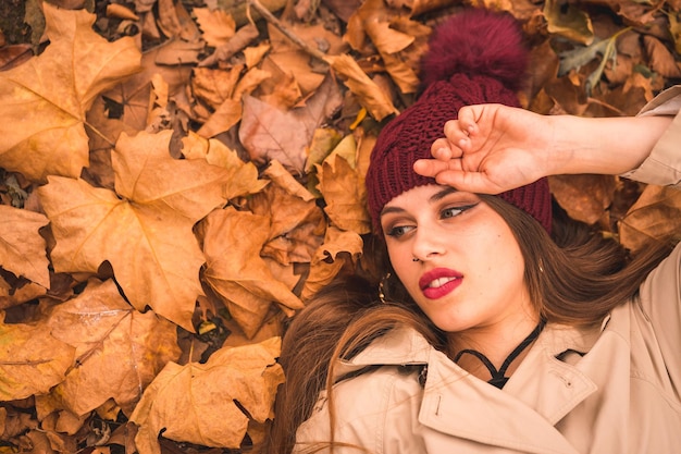 Ritratto di una donna in autunno sdraiata su foglie marroni in una foresta che guarda a sinistra copia e incolla spazio