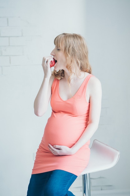 Ritratto di una donna incinta con una mela in mano. Calma futura mamma. Pausa pranzo, merenda