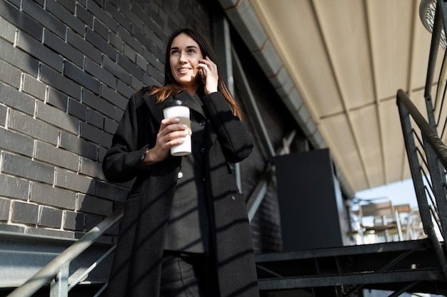 Ritratto di una donna indipendente moderna di successo in abiti da lavoro che parla su un telefono cellulare su a