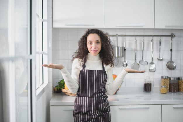 Ritratto di una donna latina che sorride felice e mostra vari gesti in cucina.