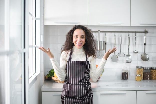 Ritratto di una donna latina che sorride felice e mostra vari gesti in cucina.