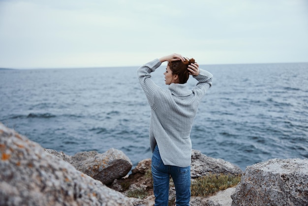 Ritratto di una donna maglioni mare nuvoloso ammirando la natura inalterata vista posteriore