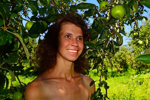 Ritratto di una donna marrone sorridente contro il fogliame verde