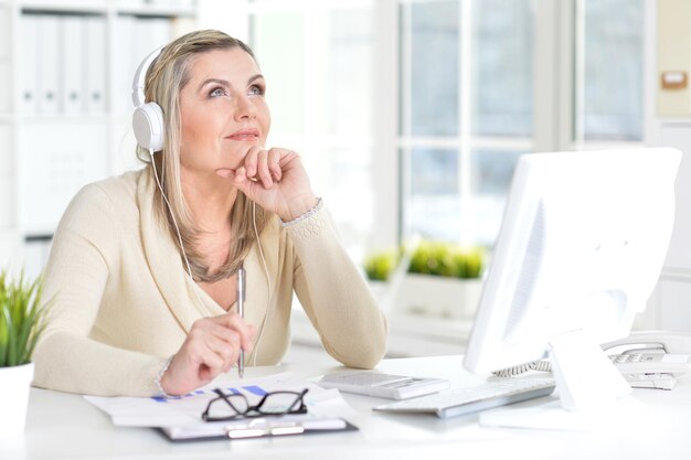 Ritratto di una donna matura in cuffia utilizzando il computer