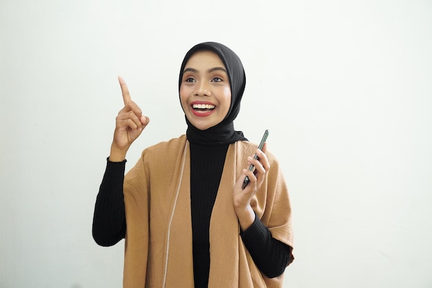 Ritratto di una donna musulmana asiatica felice che indossa l'hijab che effettua una chiamata con un telefono cellulare