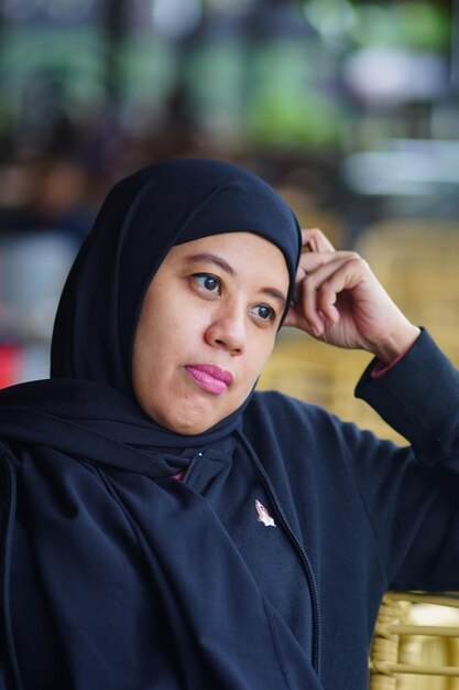 Ritratto di una donna musulmana indonesiana che indossa un hijab nero con bokeh