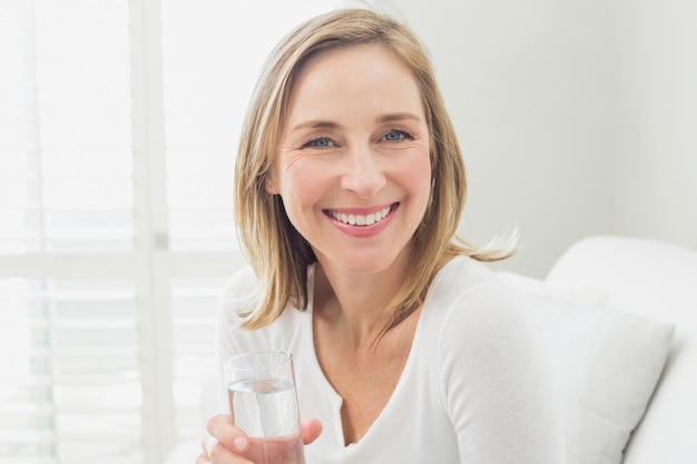 Ritratto di una donna rilassata sorridente con un bicchiere d&#39;acqua