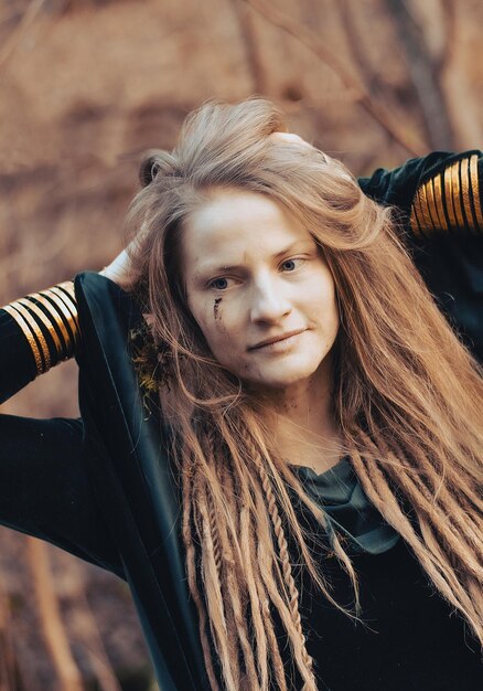 Ritratto di una donna sciamana con un braccialetto d'oro, capelli rossi e faccia sporca