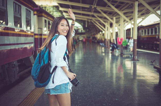 Ritratto di una donna sorridente che fa un gesto mentre si trova sulla piattaforma della stazione ferroviaria