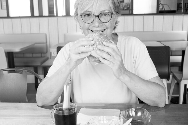 Ritratto di una donna sorridente che mangia un hamburger in un ristorante