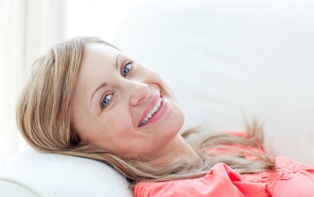 Ritratto di una donna sorridente che si trova su un divano