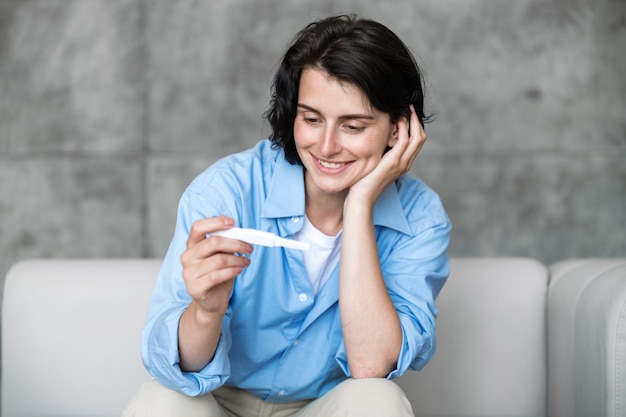 Ritratto di una donna sorridente che tiene in mano un test di gravidanza positivo