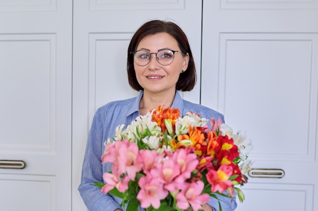Ritratto di una donna sorridente di mezza età con un mazzo di fiori