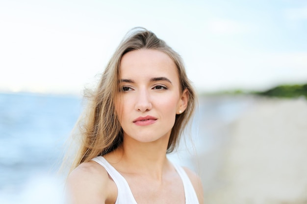 Ritratto di una donna sorridente felice nella beatitudine della felicità libera sulla spiaggia dell'oceano che si gode la natura durante le vacanze di viaggio all'aperto. Vista attraverso i fiori sfocati bianchi