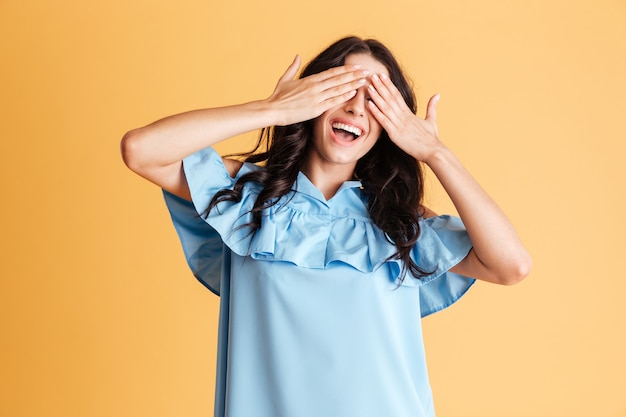 Ritratto di una donna sorridente in abito blu che copre gli occhi isolati