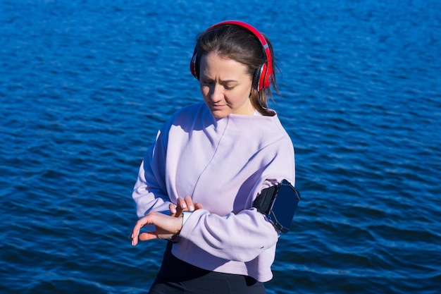 Ritratto di una donna sportiva che indossa le cuffie che guarda l'attività su un orologio fitness