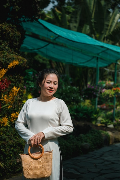 Ritratto di una donna vietnamita che indossa l'abito nazionale ao dai nel parco