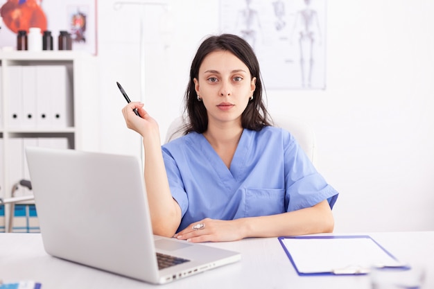 Ritratto di una dottoressa che utilizza il suo computer portatile in clinica. Medico che utilizza notebook nel posto di lavoro ospedaliero, fiducioso, competenza, medicina.