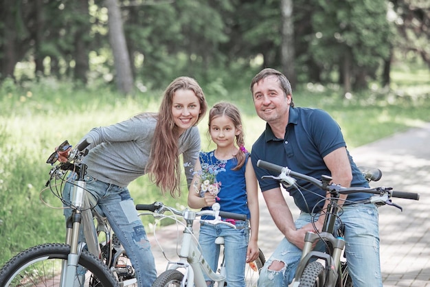 Ritratto di una famiglia felice con una piccola figlia su un giro in bicicletta